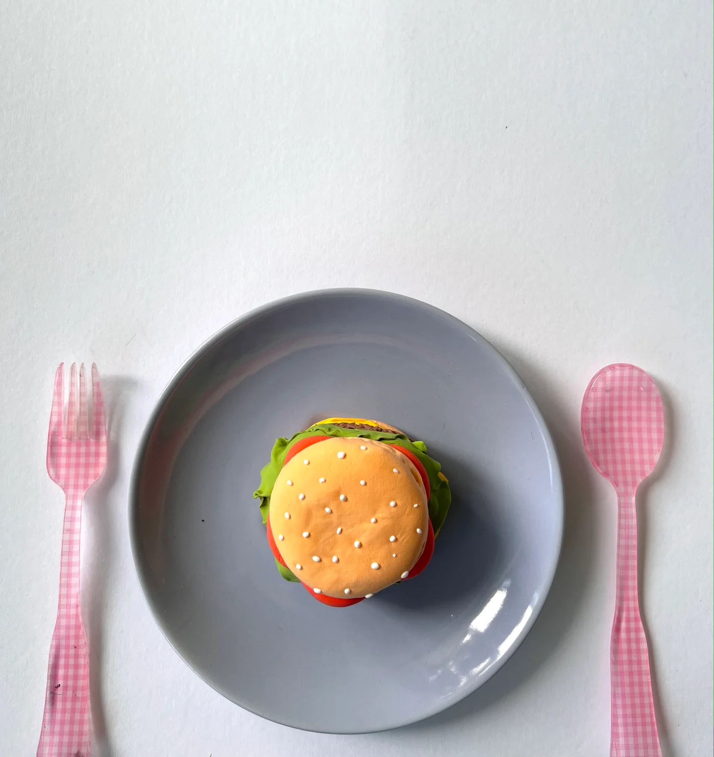 A stacked air-dry clay cheeseburger with sesame seed bun, cheese, lettuce, and tomato