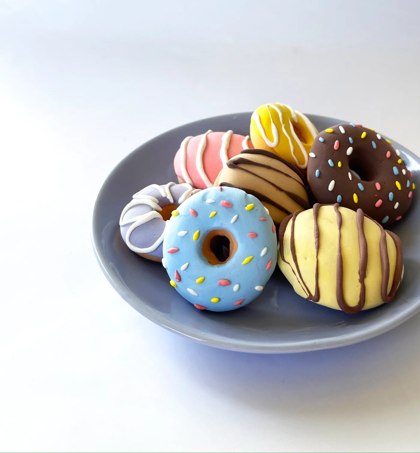 Six flavors of miniature air-dry clay donuts with frosting and sprinkles