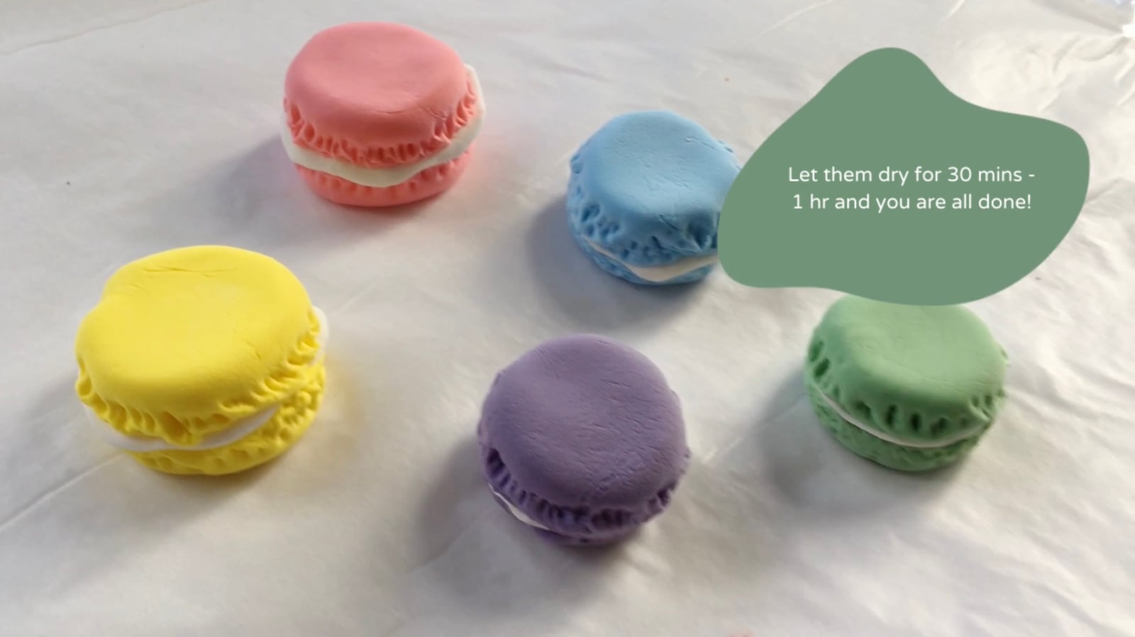 Pastel clay macarons lined up in a gradient to dry