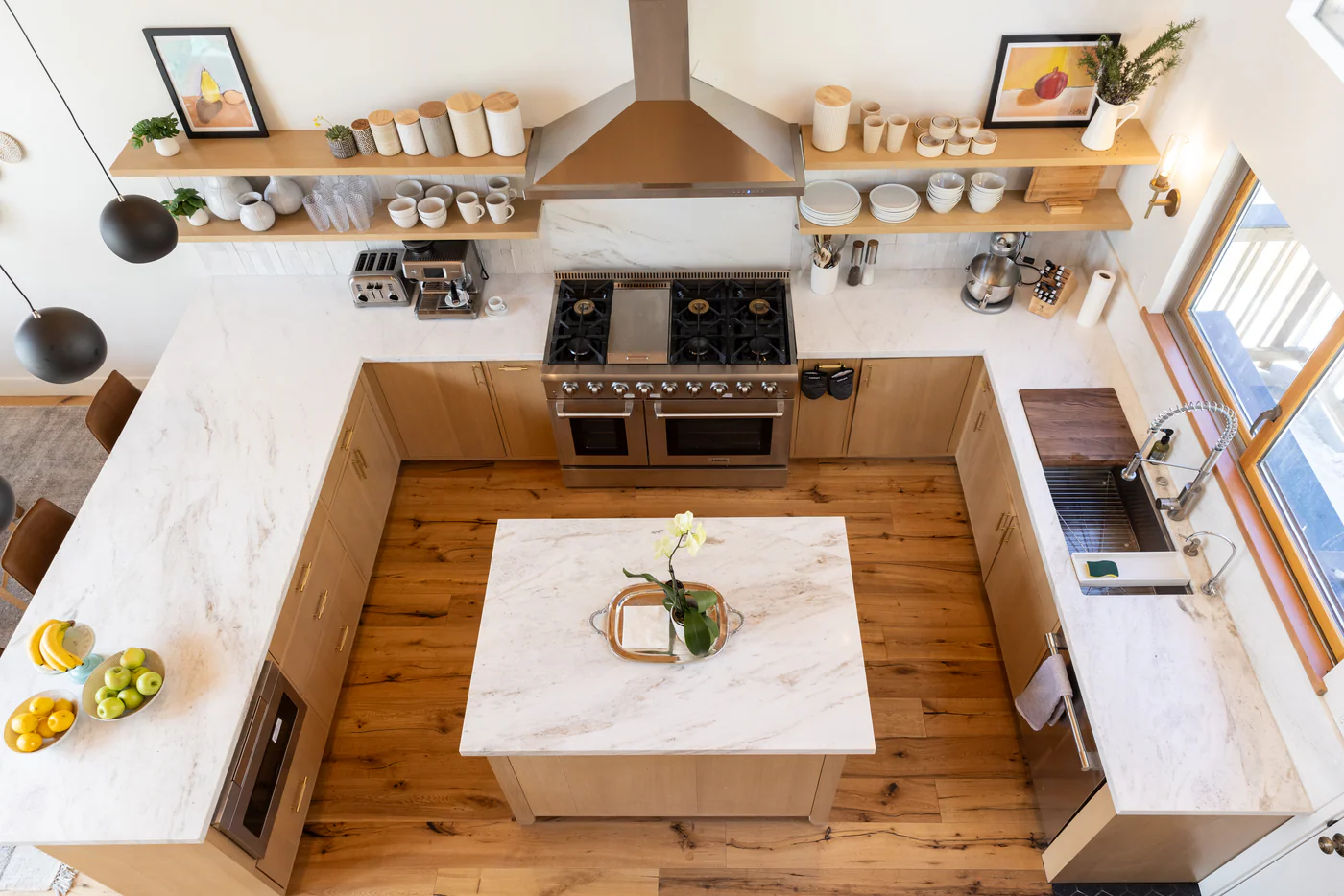 The Mammoth Kitchen after renovation, photographed from the loft above, Calacatta marble island, open shelving and custom oak cupboards
