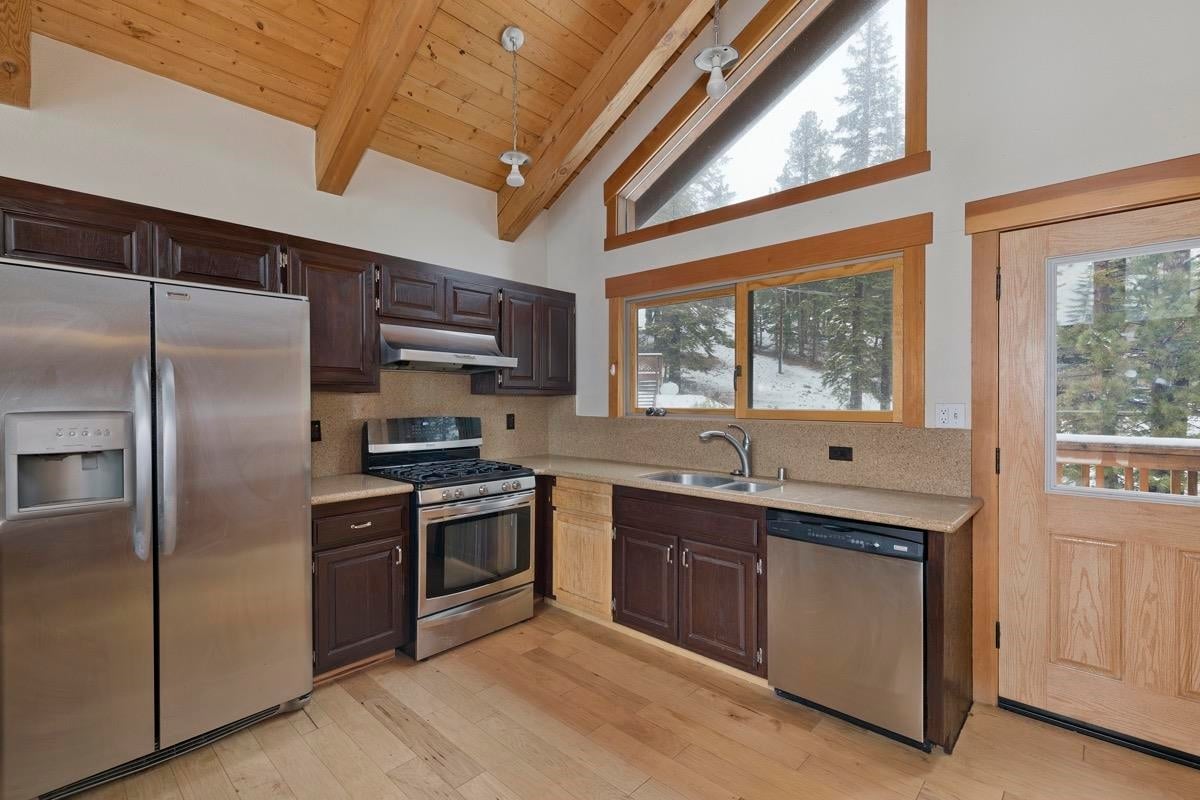 Before: 1980s kitchen at standing height, dark cabinets, stainless range and sink under the window