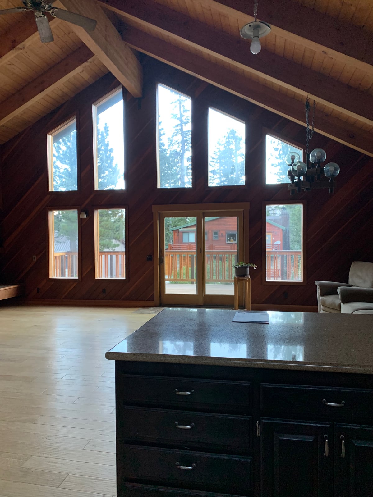 Before: 1980s ski house window wall seen from the kitchen, dark stained beams and peaked windows