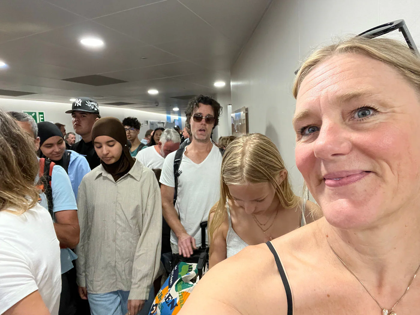 A crowded interior corridor of a ferry as foot passengers queue to disembark.